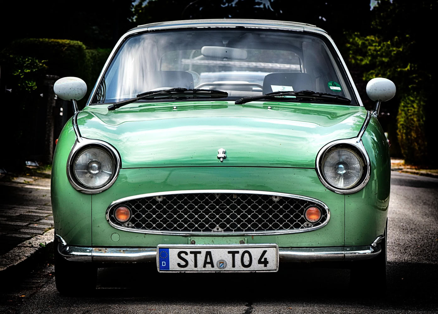 Grünes Auto mit rundem Scheinwerferdesign und deutschem Kennzeichen "STA TO 4" auf einer Straße.Oldtimer Youngtimer Bewertung